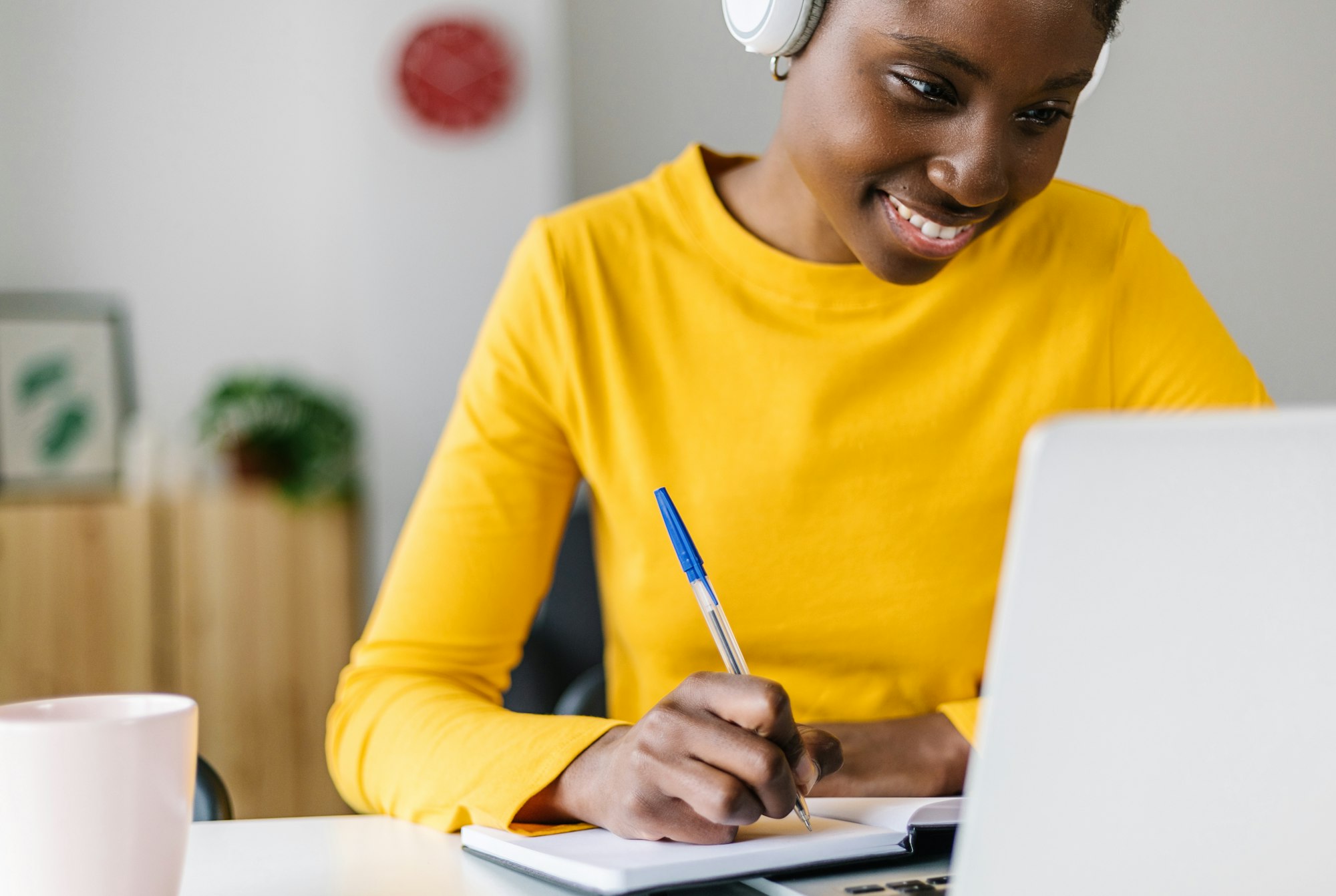 Smiling african woman student using laptop computer for online learning at home